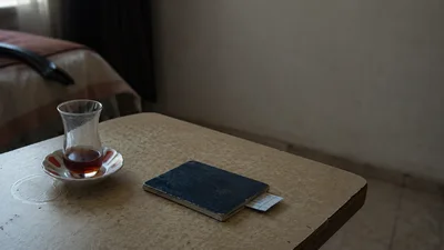 جواز سفر مستهلَك وتذكرة حافلة وكأس شاي على طاولة؛ مشهدٌ يختصر رحلة طالب طب سوري من أجل توثيق واحد.