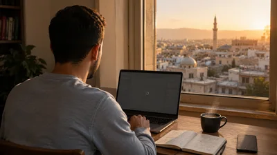 A young Syrian computer science student works at a laptop by a window in Damascus at golden hour, the screen dimmed and stalled while the old city glows warmly outside.