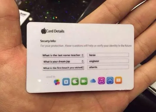 يد تحمل بطاقة بيضاء عنوانها Card Details، فيها ثلاثة أسئلة أمان مع إجاباتها، وتحتها صف من أيقونات تطبيقات آبل.
